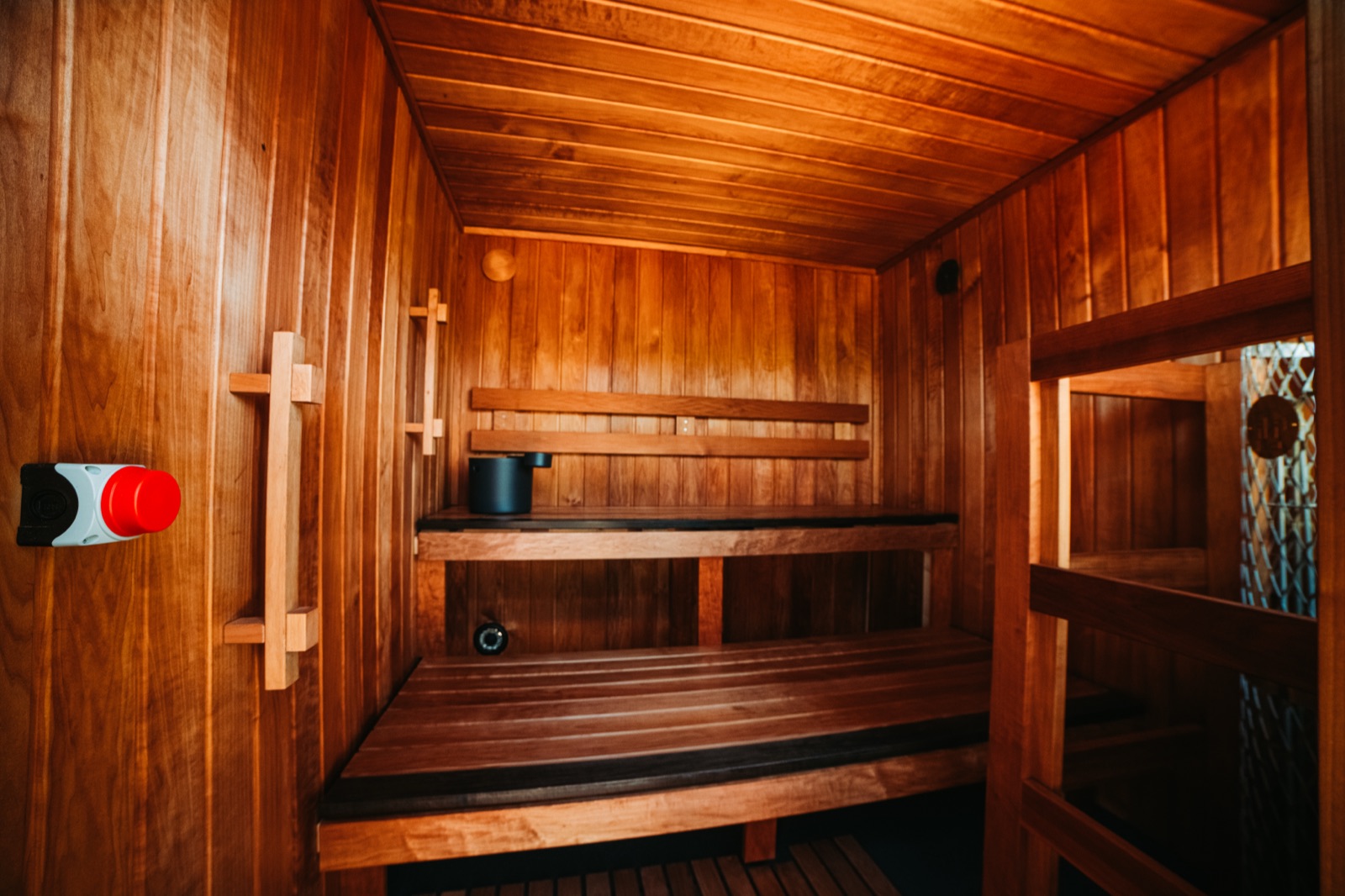 Warm cedar interior of a Sauna Box container sauna with facing benches and a stone heater