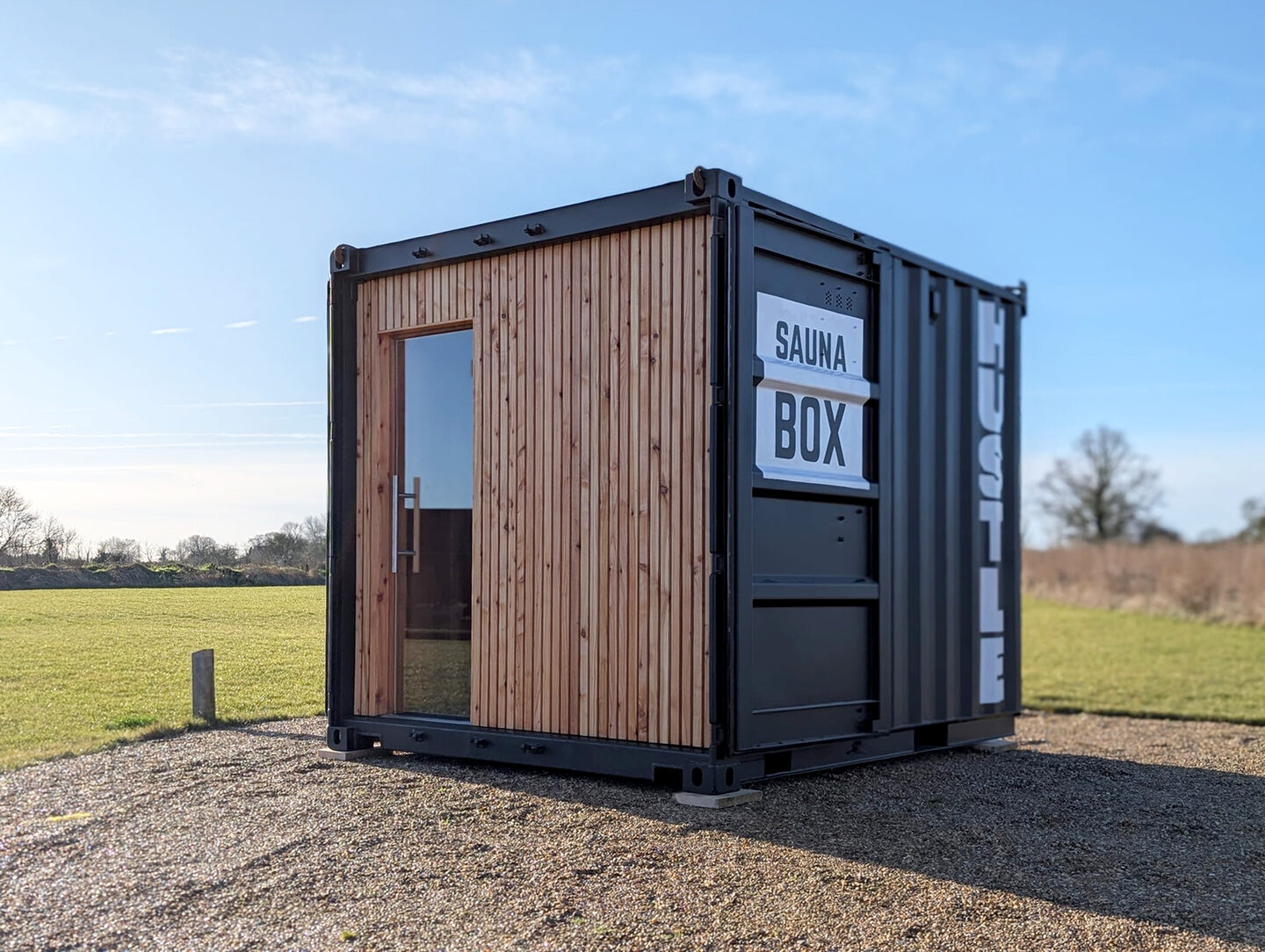 Container sauna, branded, in an open field