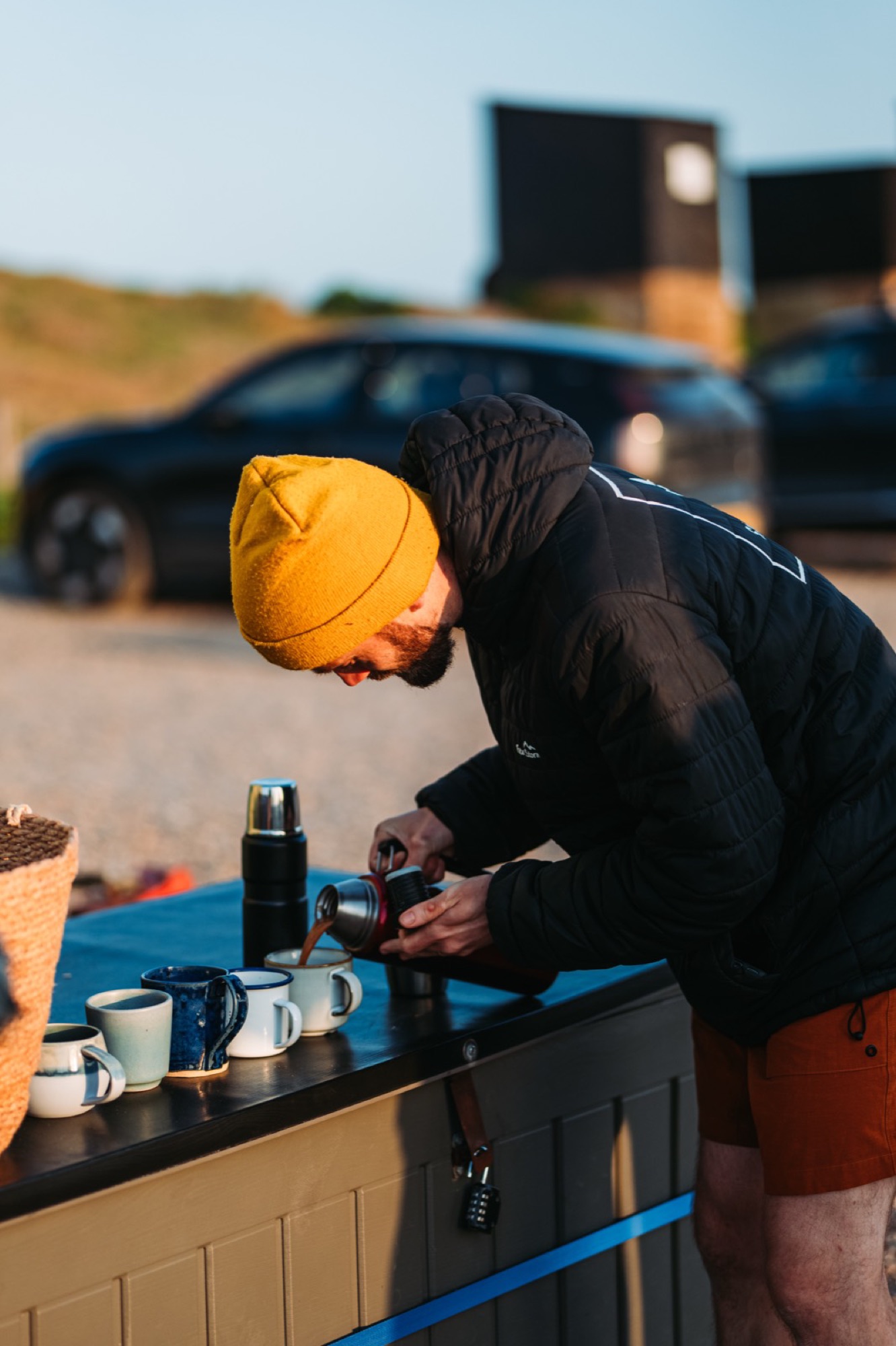 Coffee poured into handmade mugs on the sauna ledge, morning ritual by the coast